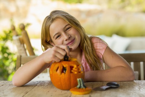 Portrait of smiling Caucasian girl with carved pumpkin