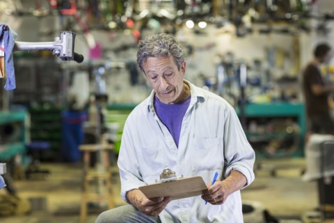 Caucasian man reading clipboard in bicycle shop