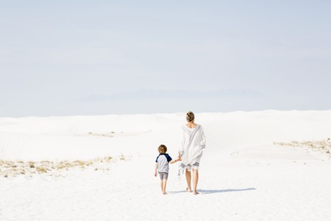 Caucasian mother and son walking in sand