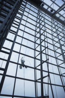 Low angle view of window washer hanging outside building