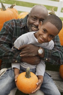 Portrait of African father and son holding pumpkin