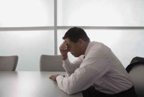Hispanic businessman with head in hand