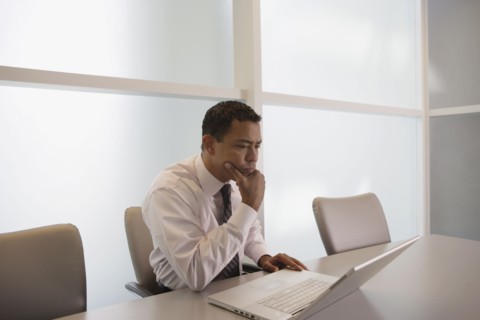 Hispanic businessman looking at laptop