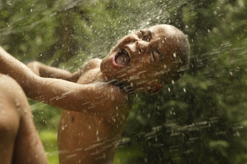 African American boy playing in sprinkler