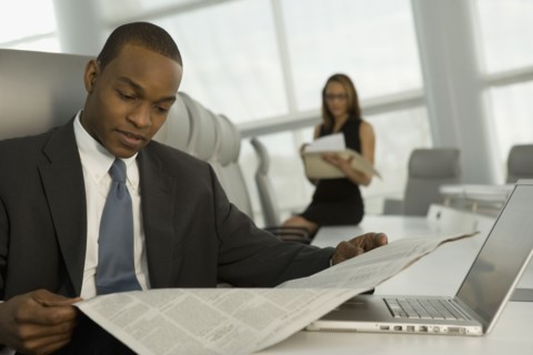 African businessman reading newspaper in conference room