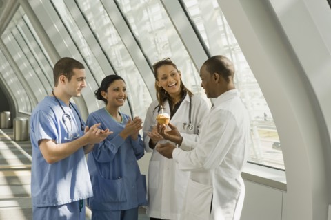 Multi-ethnic doctor and nurses giving doctor birthday cupcake