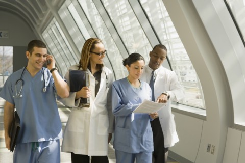 Multi-ethnic doctors and nurses reviewing paperwork in corridor