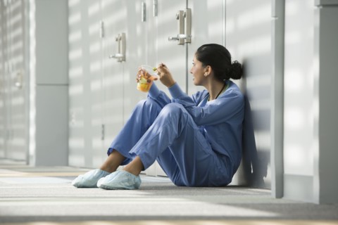 Hispanic nurse eating fruit on floor