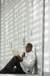 African doctor sitting on floor dictating medical record into recorder
