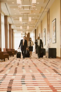 Multi-ethnic business people walking with suitcases in hotel