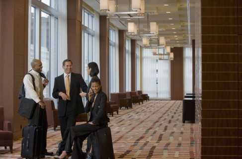 Multi-ethnic business people with suitcases talking in lobby