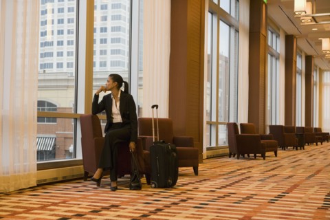African businesswoman with suitcase looking out window