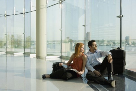 Multi-ethnic couple sitting in floor at airport