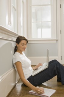 Hispanic woman using laptop and making notes