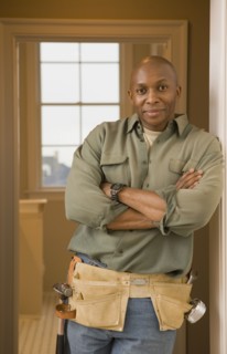 African man wearing tool belt with arms crossed