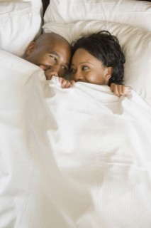African couple in bed under blanket