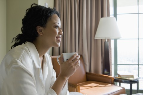 African woman drinking coffee in bedroom
