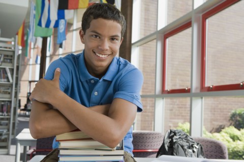 Mixed race teenager leaning on stack of books