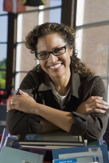 Hispanic librarian leaning on stack of books