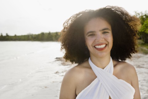 Hispanic woman smiling near ocean