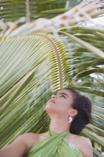 Hispanic woman in sarong near palm leaf