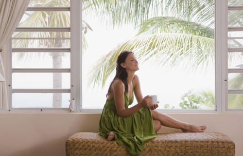 Mixed race woman drinking coffee near window