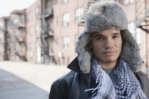 Mixed race man wearing fur hat on urban street