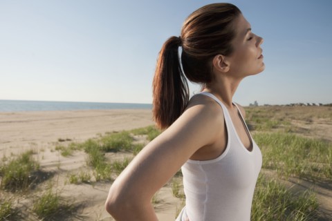 Mixed race woman standing on beach with eyes closed