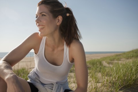 Mixed race woman in sportswear smiling on beach