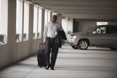 African businessman walking in parking garage with luggage