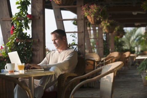 Caucasian man typing on laptop in restaurant