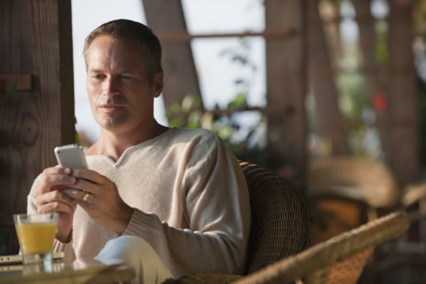 Caucasian man text messaging on cell phone in restaurant