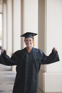 Caucasian graduate cheering in cap and gown