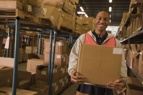Black man carrying box in warehouse