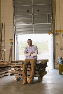 Black man sitting on pallets in warehouse