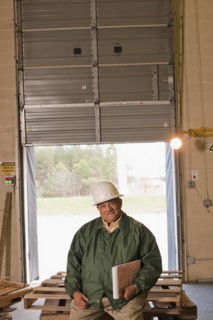 Mixed race man sitting on pallets in warehouse
