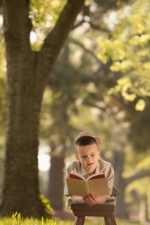 Caucasian boy reading book in yard