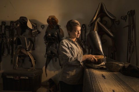 Caucasian girl caring for boots in horse stable