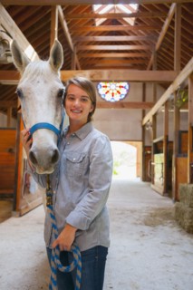 Caucasian girl smiling with horse in stable