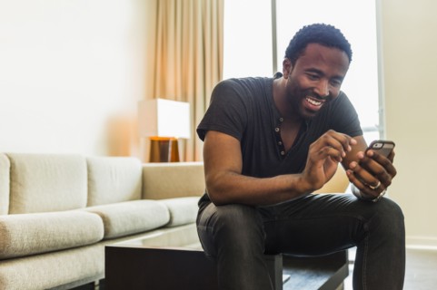 Black man using cell phone in living room