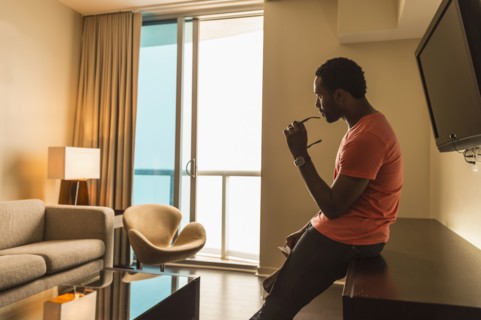 Black man leaning on credenza in living room