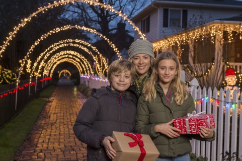 Caucasian family holding Christmas gifts on sidewalk