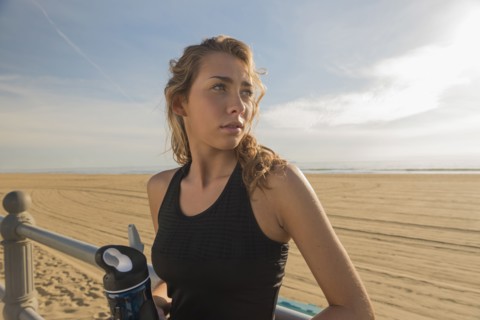 Caucasian teenage girl leaning on railing at beach
