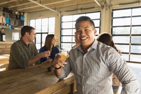 Portrait of smiling man drinking beer with friends in brew pub