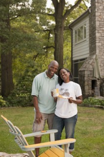 African American couple painting chair in backyard