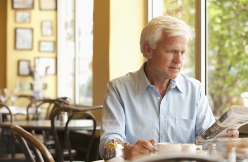 Caucasian man reading newspaper in restaurant