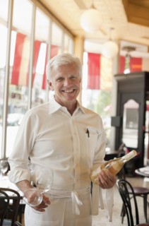 Caucasian waiter holding bottle of white wine