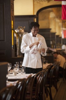 African American waitress checking wine glass in restaurant