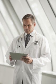 Caucasian doctor using digital tablet in hospital corridor