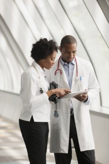 Doctors using digital tablet in hospital corridor